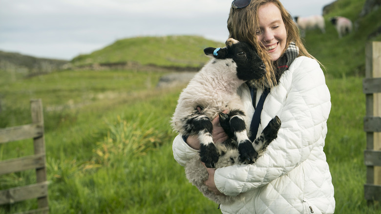 Smiling young traveler cradling lamb