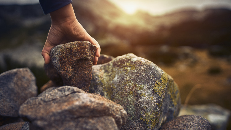 A person picks up a rock from a pile