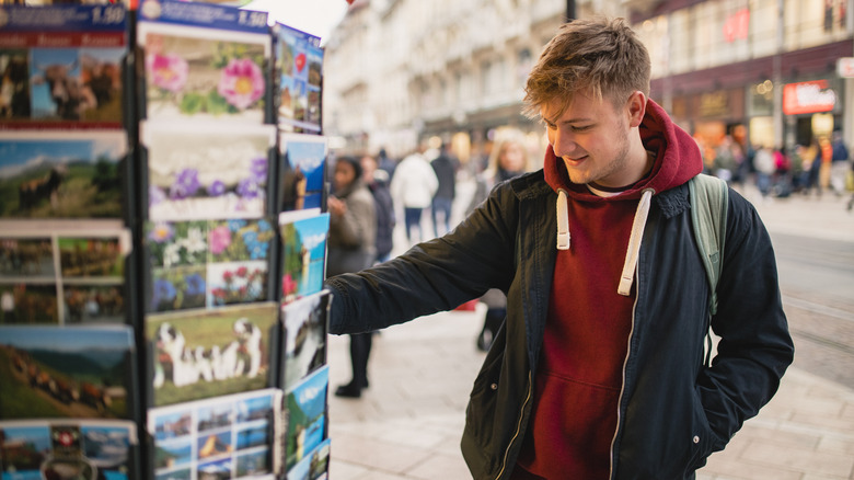 man looking at postcards