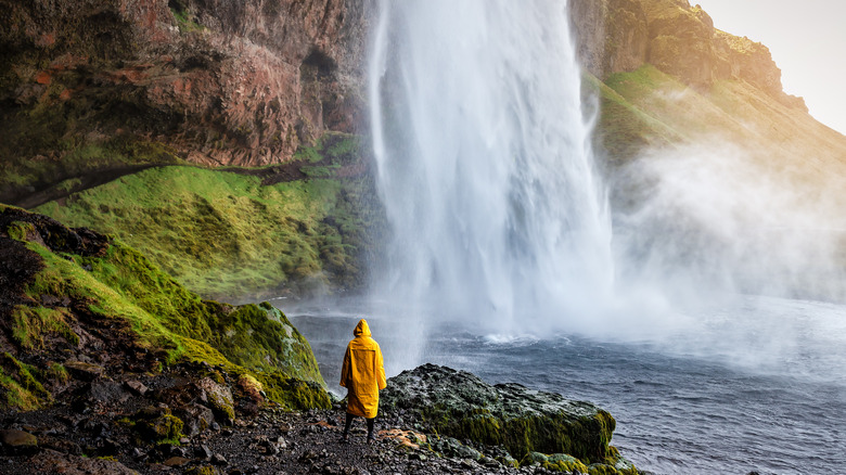 person by waterfall in raincoat