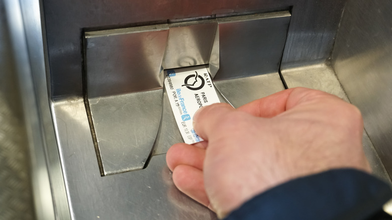 Traveler inserting ticket into turnstile