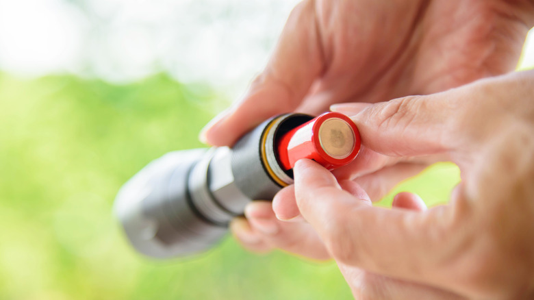 Person putting battery into flashlight