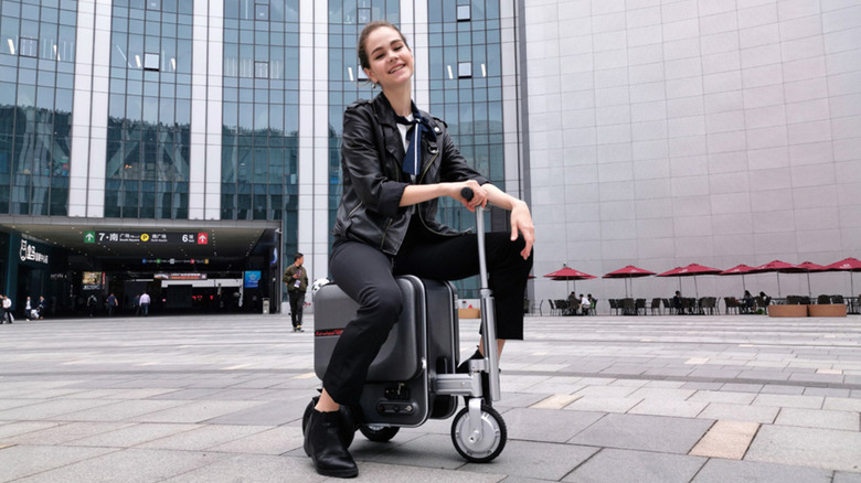 Young woman rides smart luggage