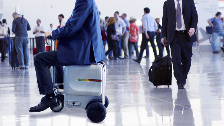 Man in suit rides luggage