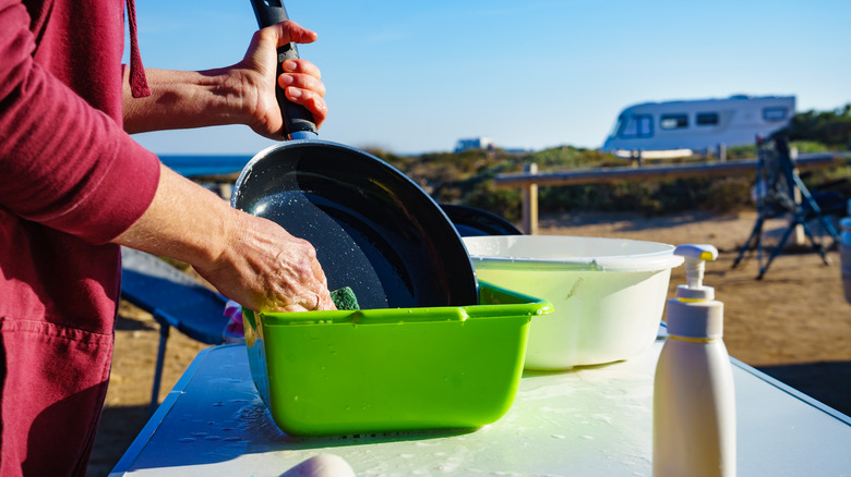 Camper washing frying pan outside