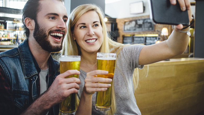 Travelers with beer taking selfie at airport