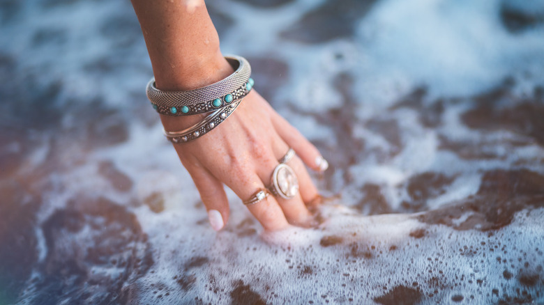 Hand with accessories dipping into water