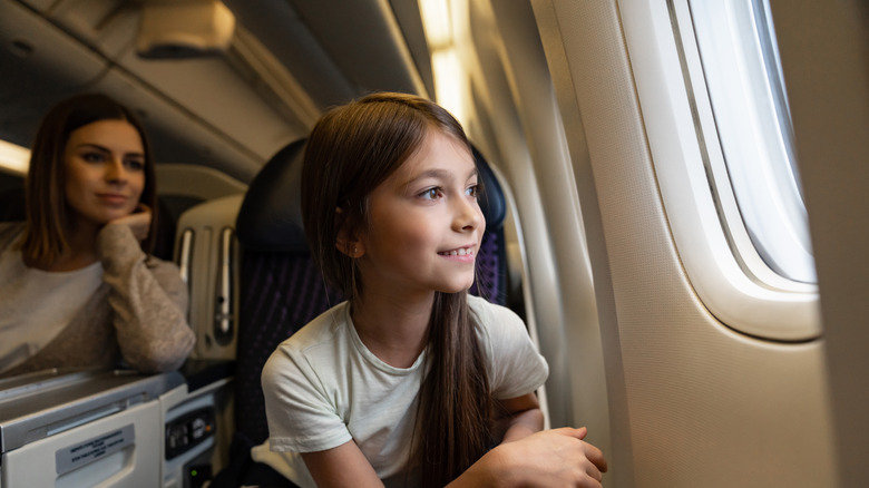 Happy girl enjoying window seat on plane