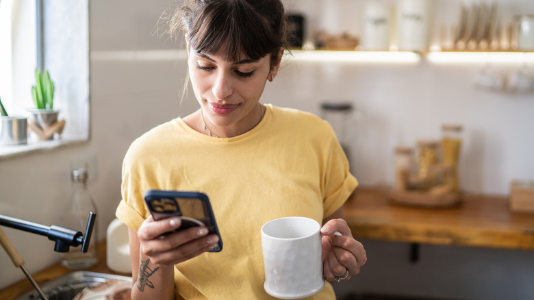 Woman drinking coffee and looking at her phone