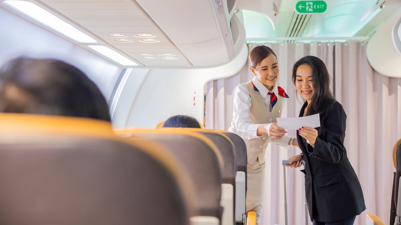 Flight attendant checking ticket at bulkhead