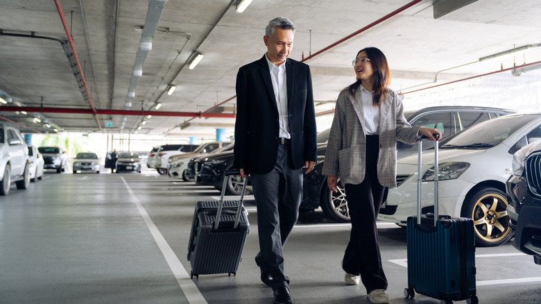 Travelers rolling suitcases through airport parking