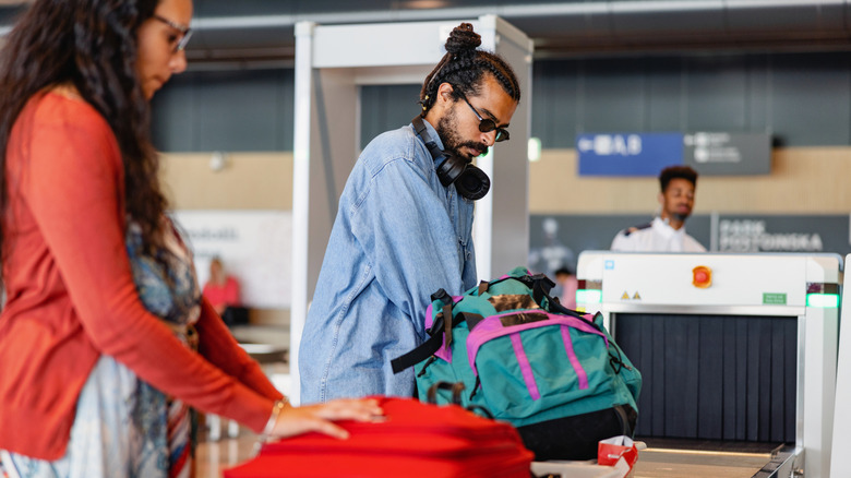 a couple preparing their bags for airport security