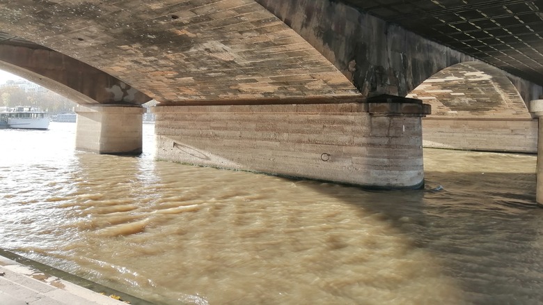 Seine River's brown water flowing under bridge