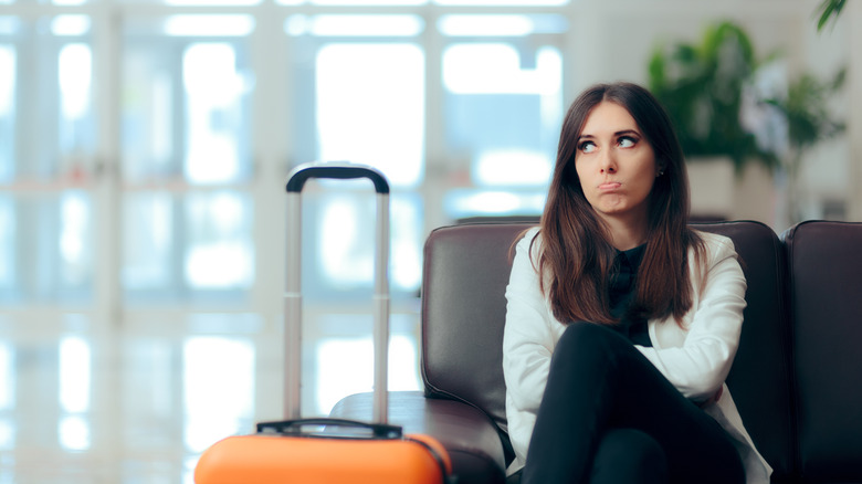 Upset woman in airport with suitcase