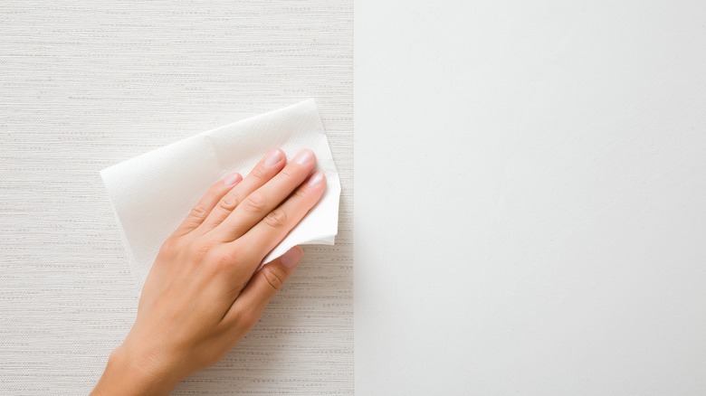 hand wiping a surface with paper towel