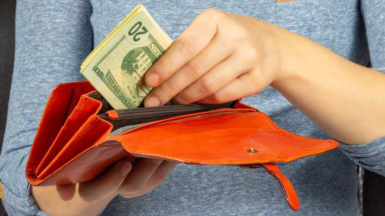 person putting money back into wallet