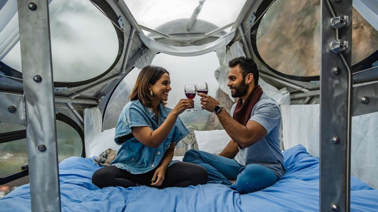 Couple clinking wine glasses in a SkyLodge capsule.