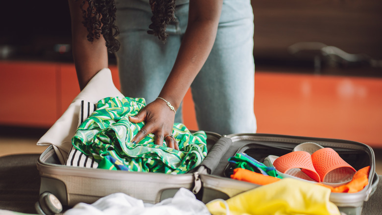 Traveler putting clothes inside suitcase